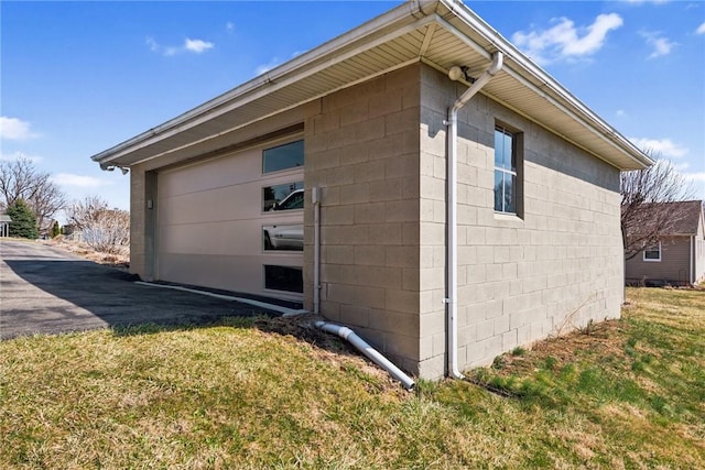 view of property exterior featuring concrete block siding, a yard, and a garage