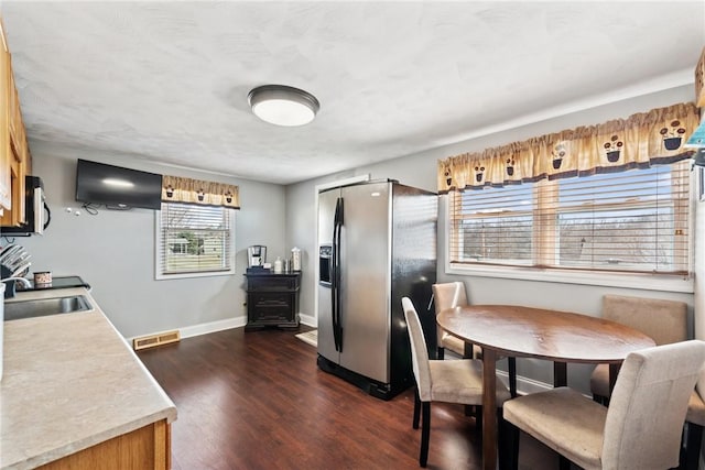 dining space with dark wood-style floors, visible vents, and baseboards