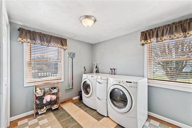 clothes washing area with visible vents, baseboards, washing machine and dryer, and laundry area