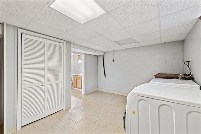 clothes washing area featuring light tile patterned floors, separate washer and dryer, concrete block wall, and laundry area