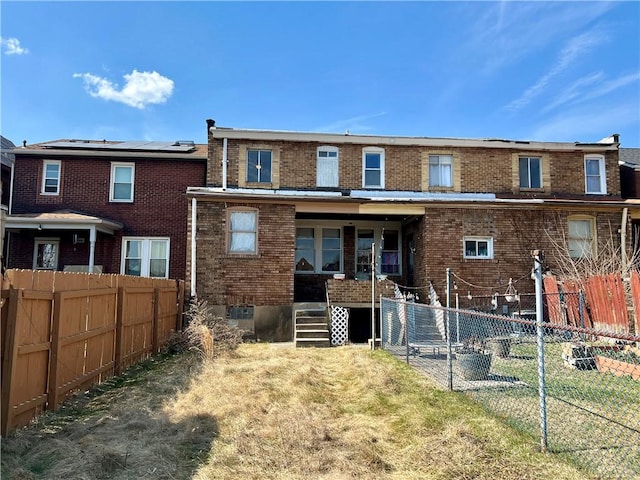 rear view of house featuring brick siding and fence