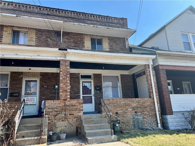 townhome / multi-family property featuring brick siding and covered porch