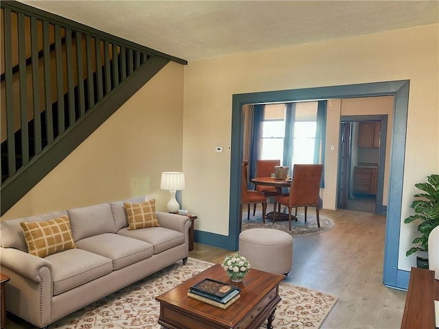 living area with stairs, baseboards, and light wood-type flooring