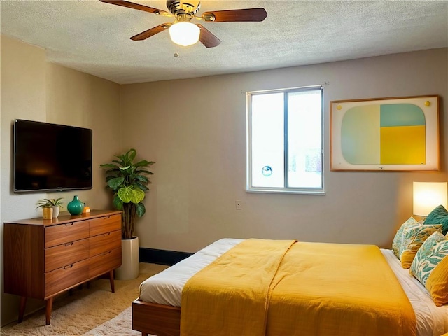 bedroom with baseboards, light colored carpet, a ceiling fan, and a textured ceiling