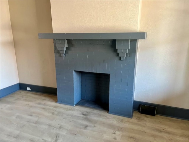 details featuring a fireplace, wood finished floors, and baseboards