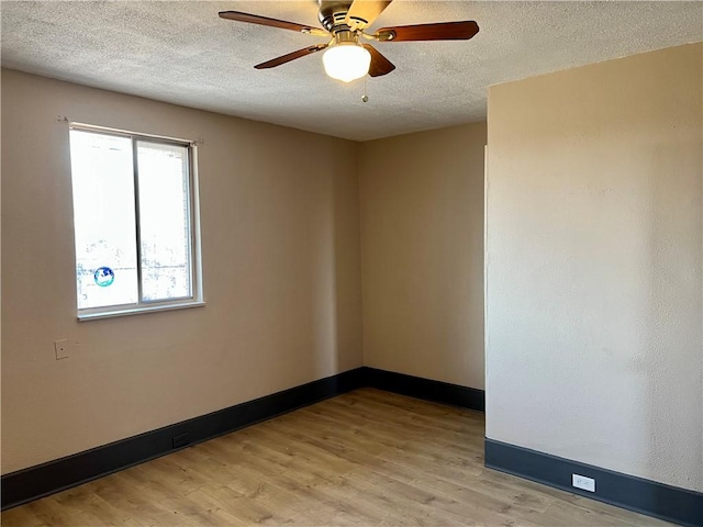 spare room featuring light wood-style flooring, a textured ceiling, baseboards, and a ceiling fan