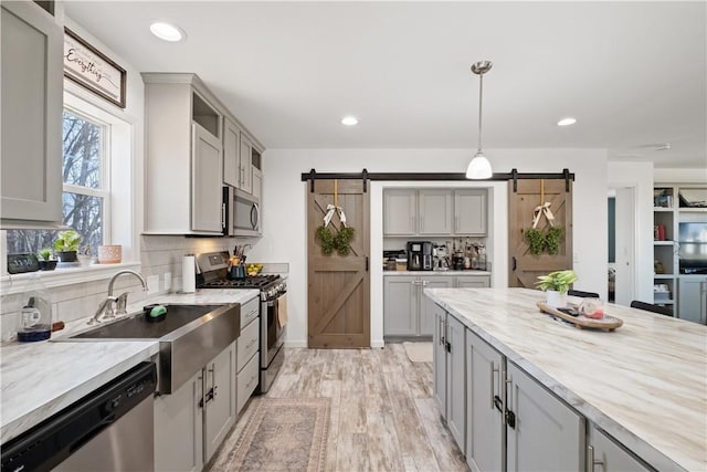 kitchen featuring a barn door, gray cabinetry, and stainless steel appliances