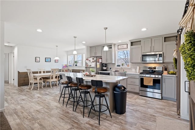 kitchen featuring a kitchen breakfast bar, gray cabinetry, tasteful backsplash, and stainless steel appliances