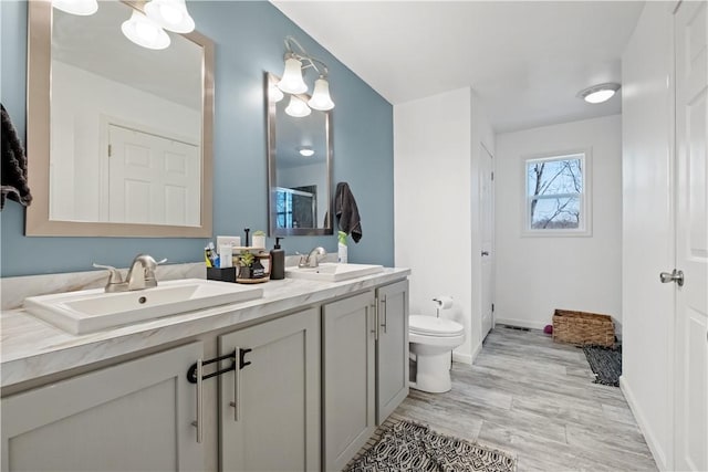 full bath with double vanity, toilet, baseboards, and a sink