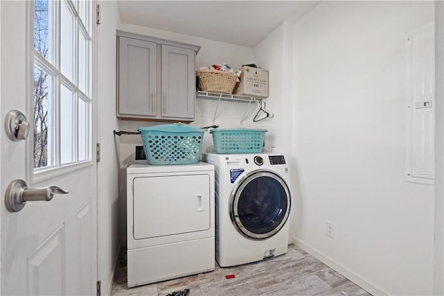 laundry room with light wood-style flooring, cabinet space, baseboards, and washing machine and clothes dryer