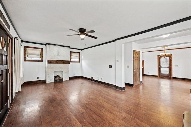 unfurnished living room with baseboards, dark wood-type flooring, crown molding, and ceiling fan with notable chandelier