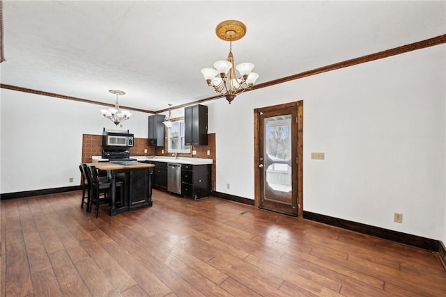 kitchen with a chandelier, appliances with stainless steel finishes, light countertops, and dark wood-type flooring