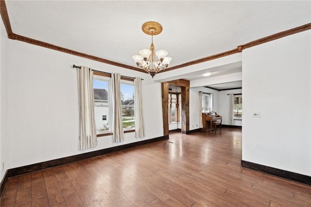 unfurnished room with hardwood / wood-style floors, a wealth of natural light, and a chandelier