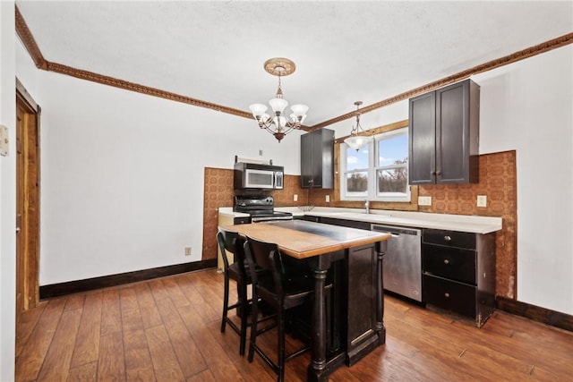 kitchen with tasteful backsplash, dark wood-style floors, stainless steel appliances, light countertops, and a chandelier