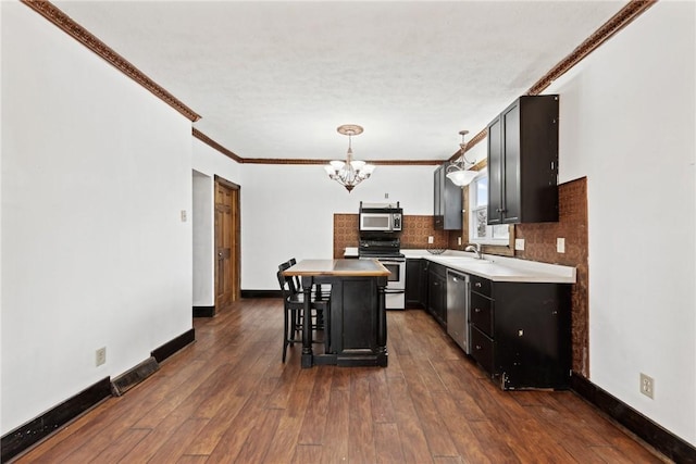 kitchen featuring a notable chandelier, a sink, dark wood finished floors, appliances with stainless steel finishes, and baseboards