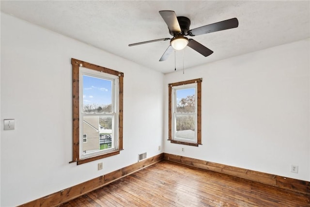 empty room with visible vents, baseboards, a healthy amount of sunlight, and hardwood / wood-style floors