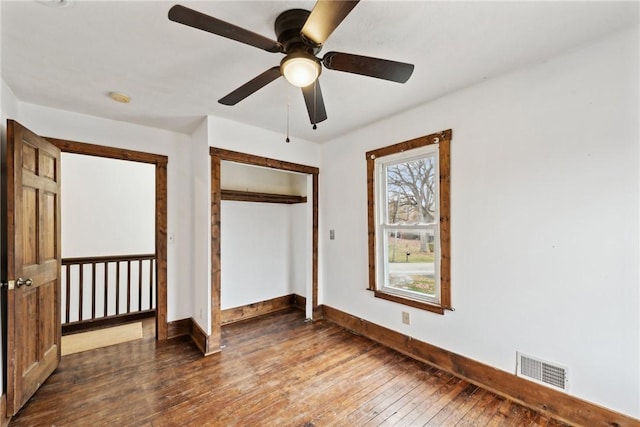 unfurnished bedroom with hardwood / wood-style flooring, baseboards, visible vents, and a closet