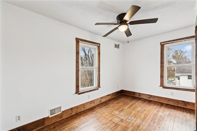 empty room featuring a ceiling fan, visible vents, and wood-type flooring