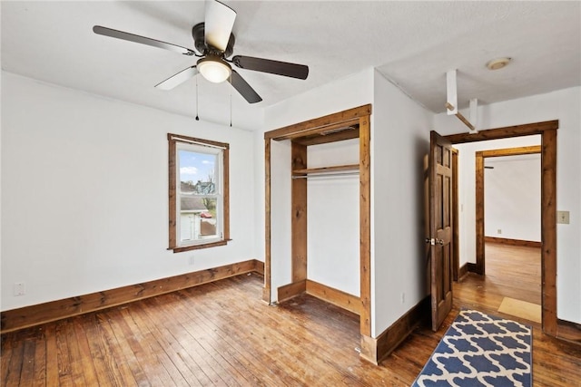 unfurnished bedroom featuring a closet, a ceiling fan, baseboards, and hardwood / wood-style flooring