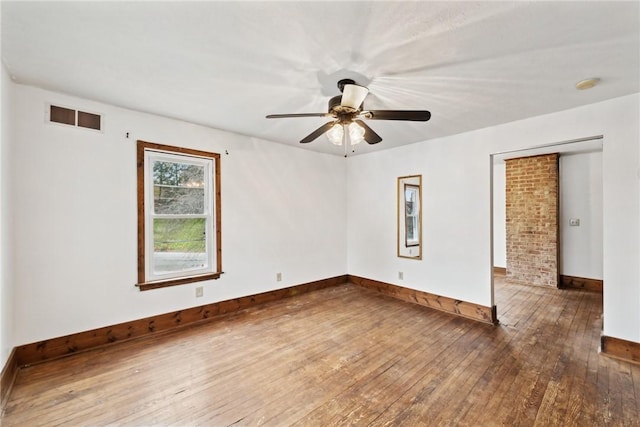 unfurnished room featuring a ceiling fan, visible vents, wood-type flooring, and baseboards