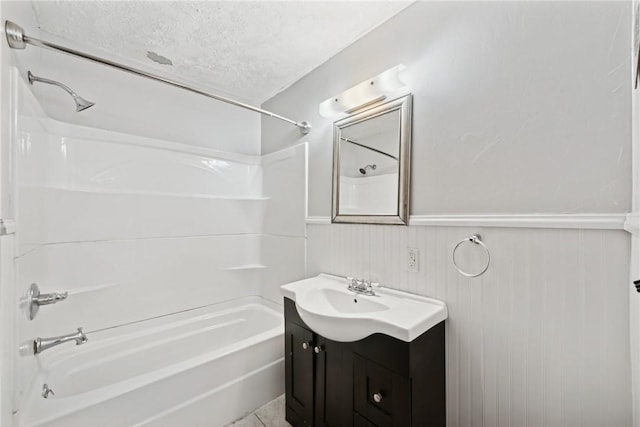 bathroom with wainscoting, a textured ceiling, vanity, and  shower combination