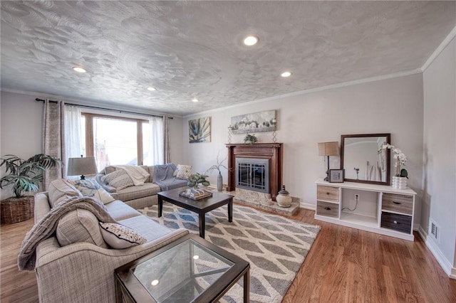 living area with a glass covered fireplace, wood finished floors, and crown molding