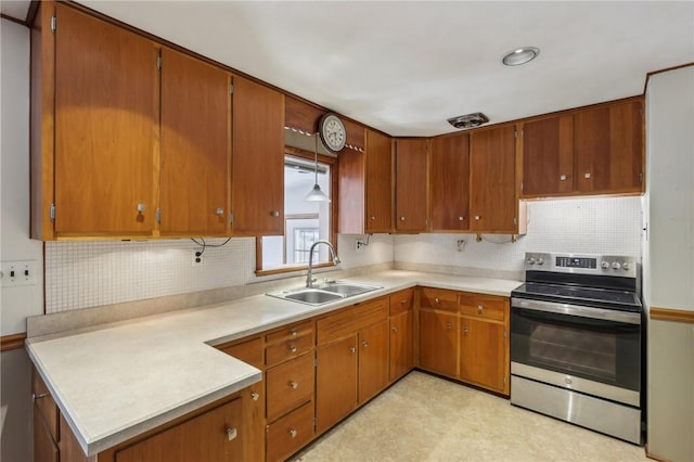 kitchen with electric stove, a sink, brown cabinetry, light countertops, and decorative backsplash