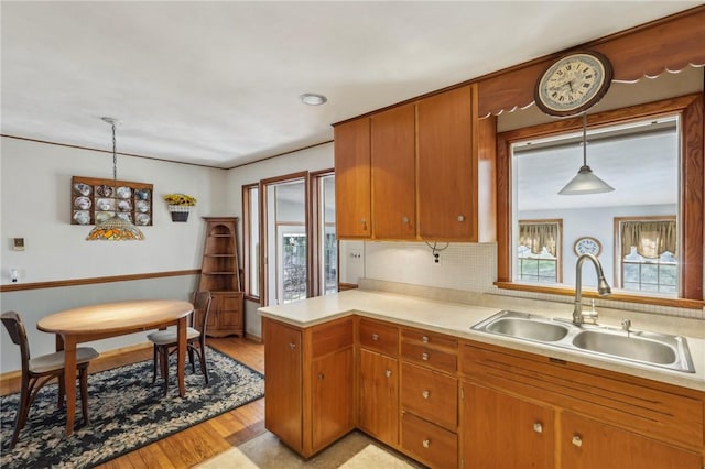 kitchen featuring a sink, brown cabinets, hanging light fixtures, and light countertops