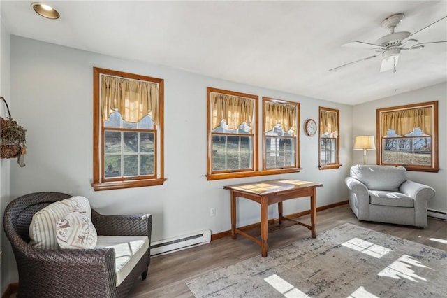 sitting room with baseboards, vaulted ceiling, baseboard heating, wood finished floors, and a ceiling fan