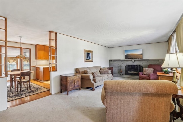 living room featuring light colored carpet, a brick fireplace, and light wood-style flooring