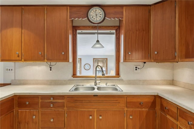 kitchen featuring a sink, decorative backsplash, brown cabinetry, and light countertops