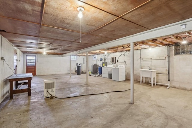 below grade area featuring concrete block wall, separate washer and dryer, and a sink