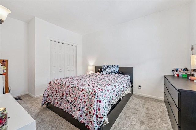 bedroom featuring visible vents, baseboards, a closet, and light carpet