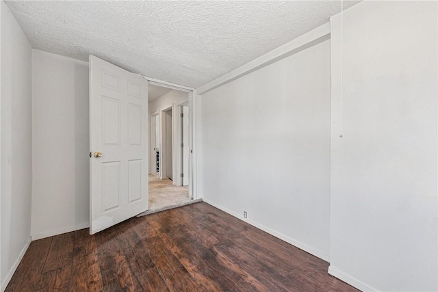 spare room with a textured ceiling, baseboards, and wood finished floors