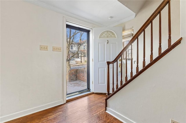 foyer entrance featuring crown molding, stairway, wood finished floors, and baseboards