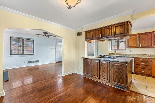 kitchen with a ceiling fan, visible vents, arched walkways, dark wood-type flooring, and crown molding