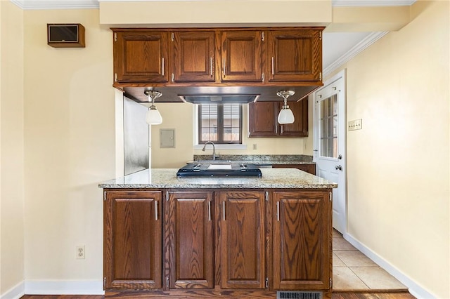 kitchen with a peninsula, stovetop, light stone counters, and crown molding