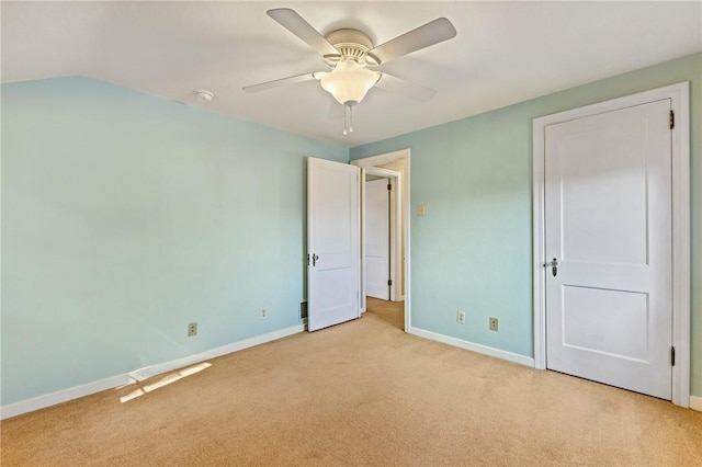 unfurnished bedroom featuring light carpet, a ceiling fan, and baseboards