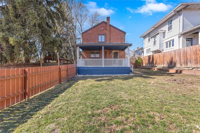 rear view of house with brick siding, a lawn, and a fenced backyard