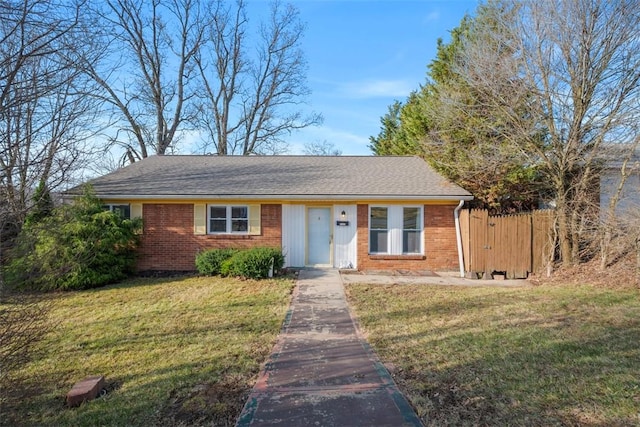 view of front of property with brick siding, fence, a front yard, and roof with shingles