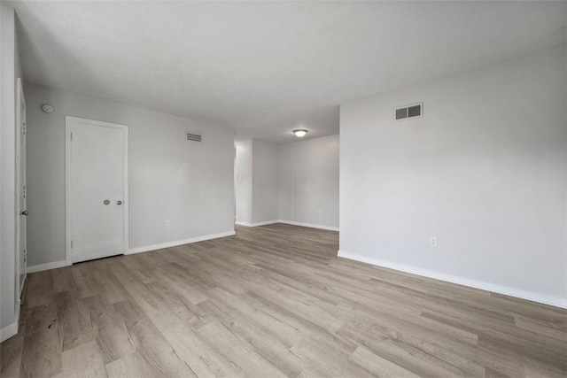 empty room with visible vents, baseboards, and wood finished floors