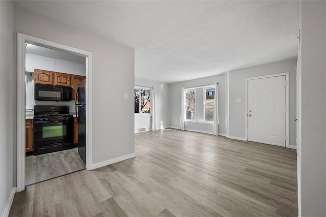 unfurnished living room featuring light wood finished floors and baseboards