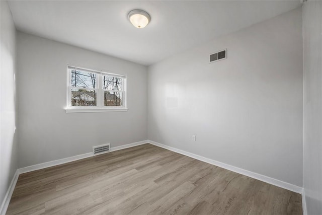 spare room featuring visible vents, baseboards, and wood finished floors