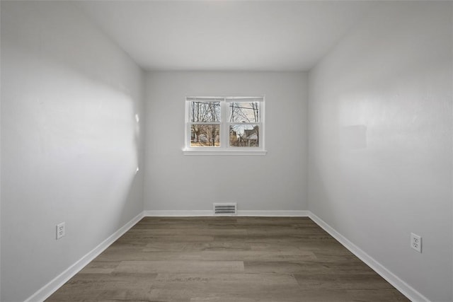 unfurnished room with dark wood finished floors, visible vents, and baseboards