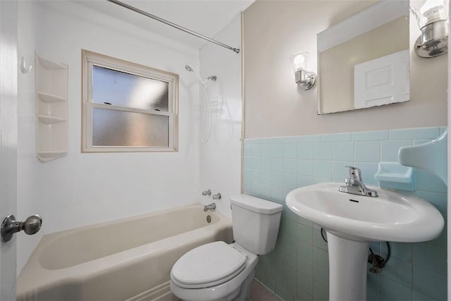 bathroom with a wainscoted wall, toilet, tile walls, and washtub / shower combination