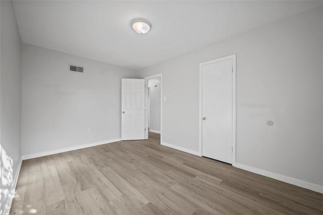 unfurnished bedroom featuring visible vents, baseboards, and wood finished floors