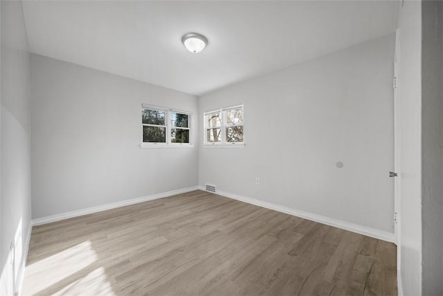 unfurnished room featuring visible vents, baseboards, and wood finished floors