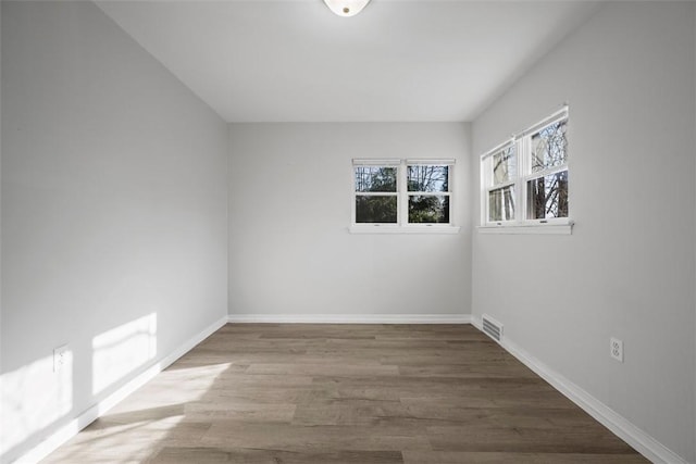 empty room featuring visible vents, baseboards, and wood finished floors