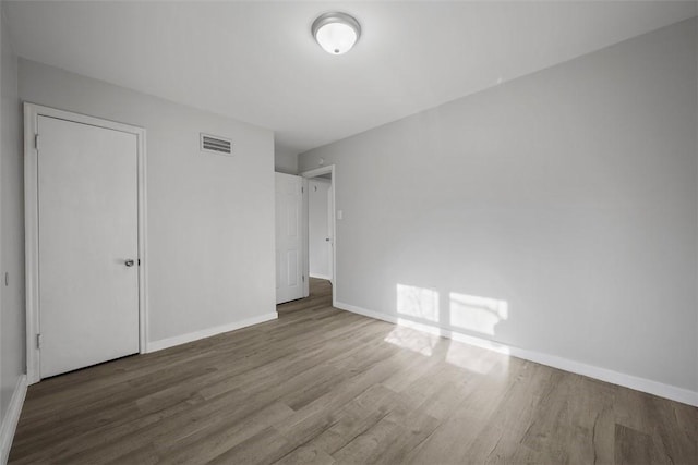 unfurnished bedroom with wood finished floors, visible vents, and baseboards