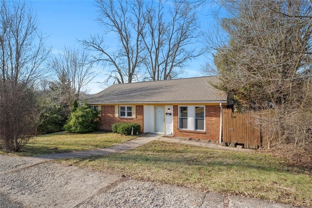 ranch-style house with a front yard, brick siding, and roof with shingles